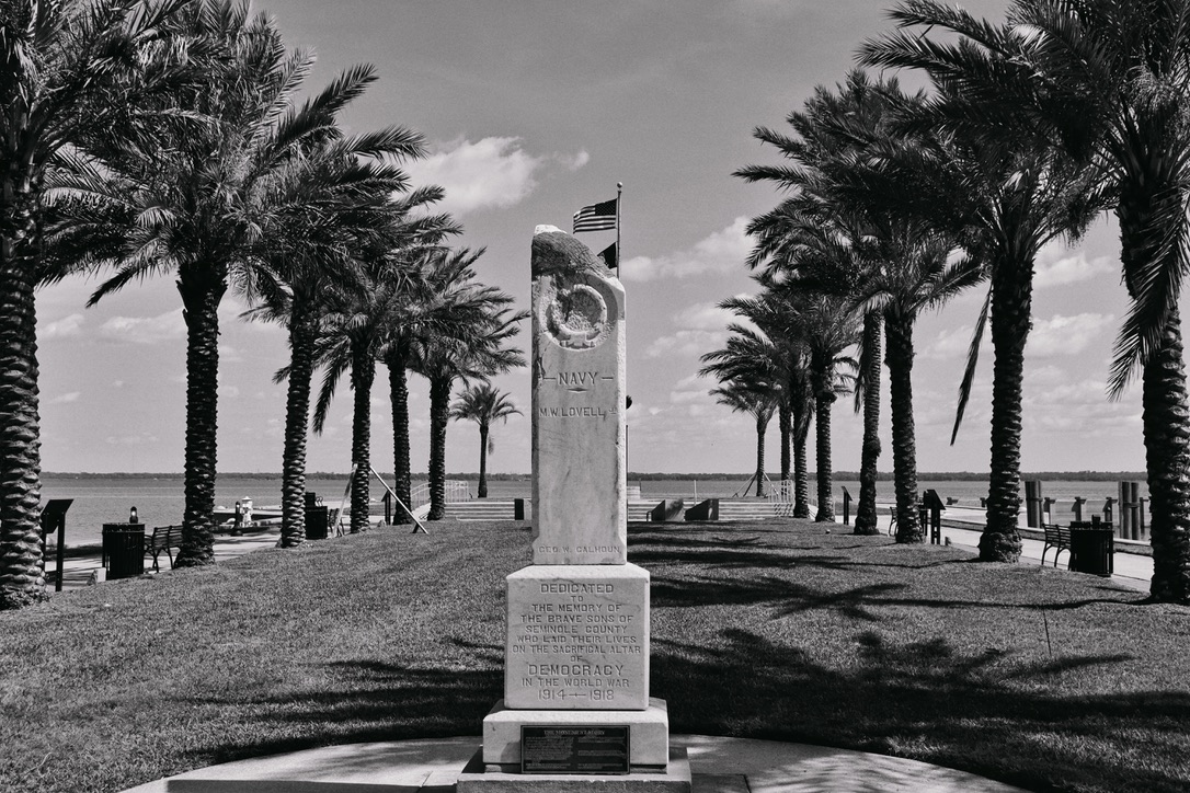 Black and white photo of a memorial framed by palm trees